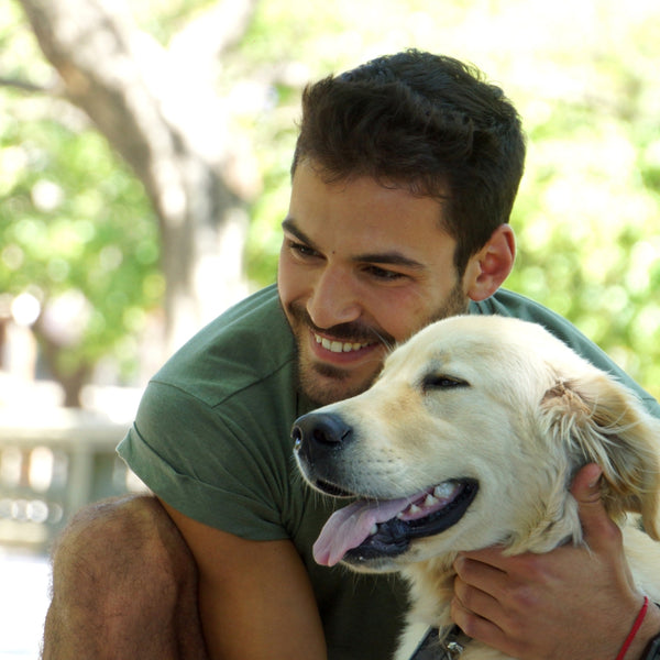 Man smiling and hugging his happy golden retriever outdoors together